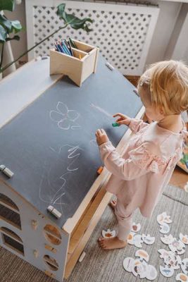 Une petite enfant utilise des craies sur le tableau du bureau Montessori