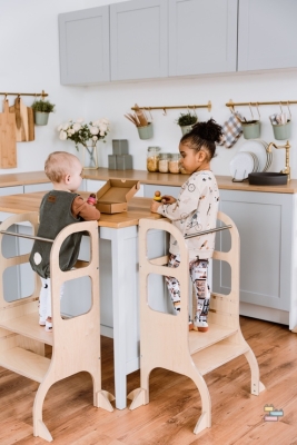 Tour Montessori ajustable couleur bois avec enfant dessus à différents niveaux